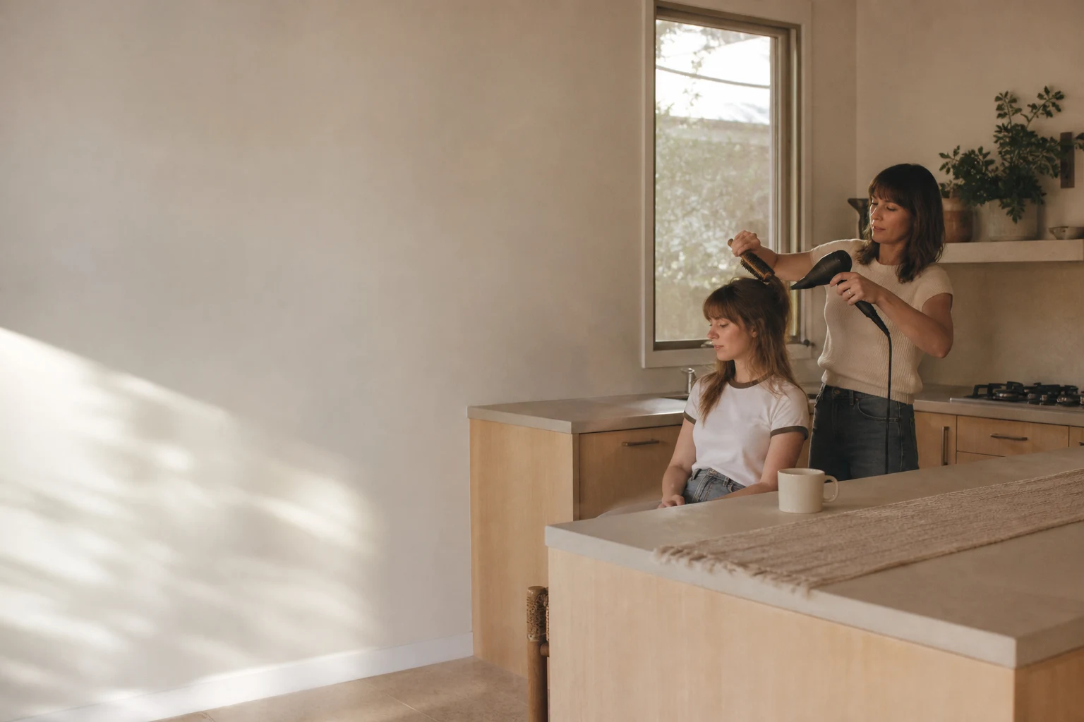 A stylist giving a blowout at a client's kitchen island in her Austin home